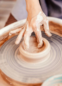 The woman sculpts from clay. modeling on a potter's wheel. hands are molded from clay.  workshop.