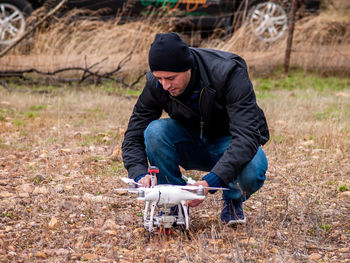 Man crouching by drone on grass