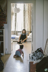 Baby girl crawling towards mother at home