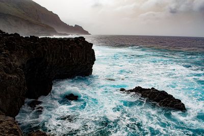 Scenic view of rocks in sea against sky