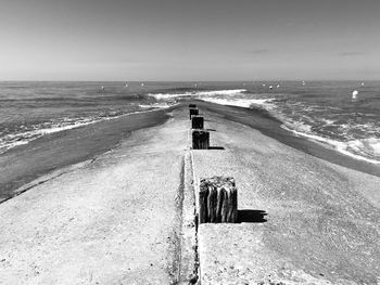 Pier on beach with waves in motion 