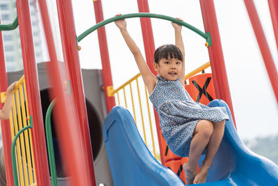 Portrait of cute hanging on slide at playground