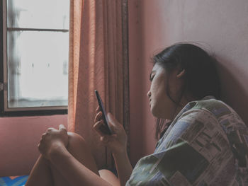 Side view of man using mobile phone at home