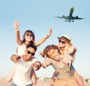 Portrait of cheerful couple with airplane in background