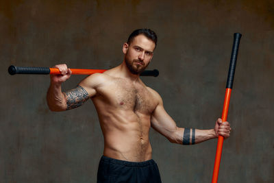 Portrait of shirtless man against wall