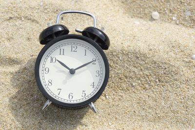Close-up of alarm clock on sand
