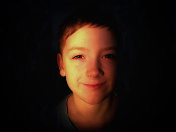 Close-up portrait of boy against black background