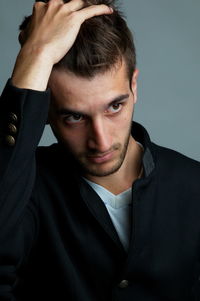 Close-up of thoughtful young man over gray background