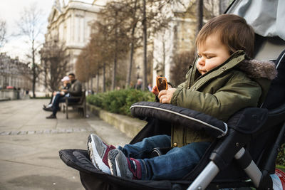 Side view of boys sitting on mobile phone