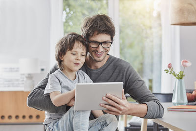 Happy father and son using tablet at home together