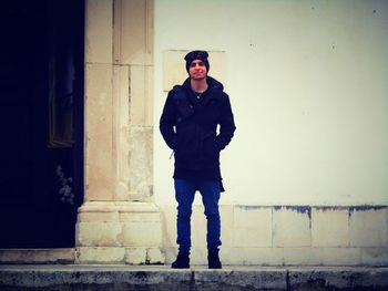 Portrait of young man standing against wall