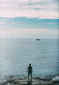 Rear view of man looking at sea against sky