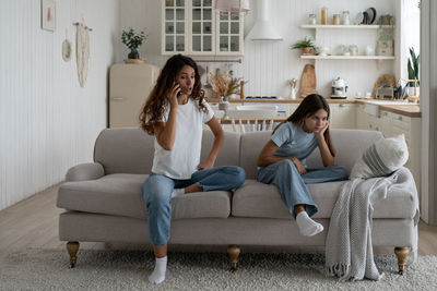 Portrait of woman using mobile phone while sitting on sofa at home