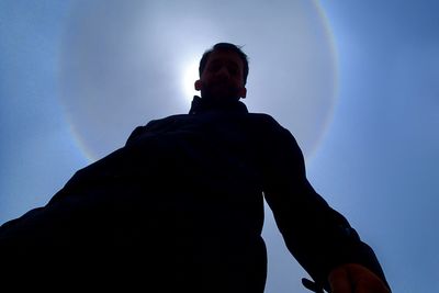 Low angle view of man looking against blue sky