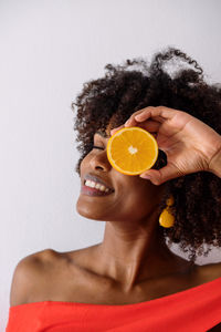 Black woman with afro hair holding cut orange halves smiling