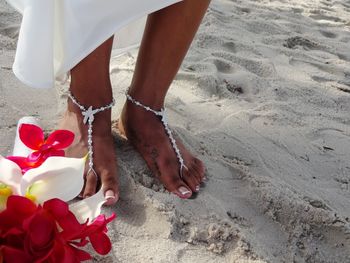 Low section of woman wearing jewelry while standing on beach