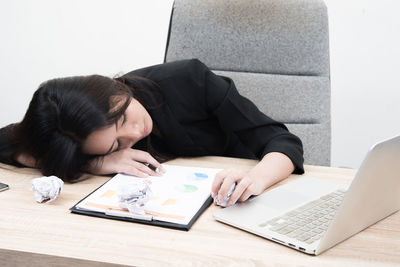 Young businesswoman napping by laptop on table