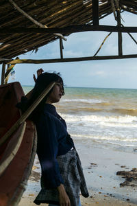 Side view of woman on beach against sky