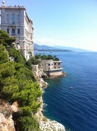 Buildings by sea against sky