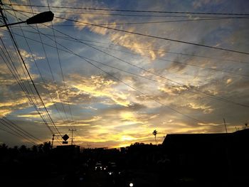 Low angle view of silhouette electricity pylon against sky during sunset
