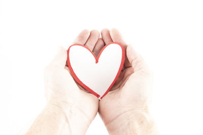 Low section of woman holding heart shape against white background