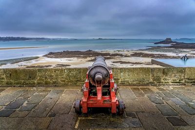 Cannon on beach against sky