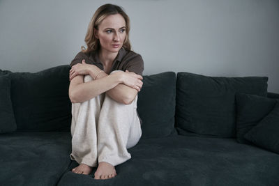 Sad woman sitting on sofa at home