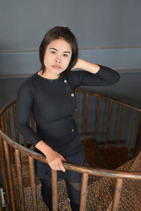 High angle portrait of beautiful woman standing on steps against wall