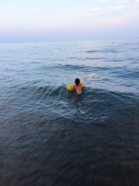 Girl swimming in sea against sky