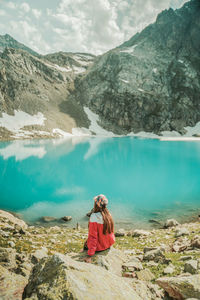 Woman sitting on rocks against mountains