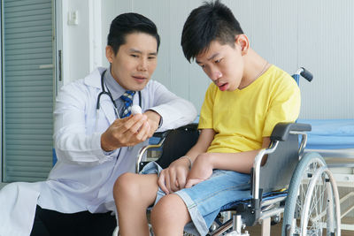 Boy sitting in front of two people