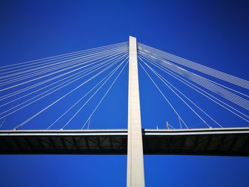 Low angle view of suspension bridge against clear blue sky