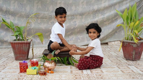 Shot of indian girl tying rakhi to brother hand during raksha bandhan festival at home.