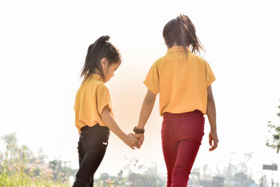 Rear view of women standing against sky