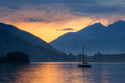 Sailboat on lake against sky during sunset