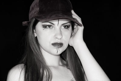 Portrait of young woman against black background