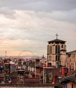 Buildings in city against cloudy sky