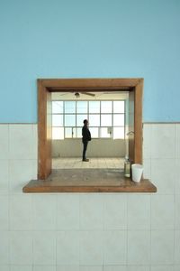 Rear view of woman standing against wall