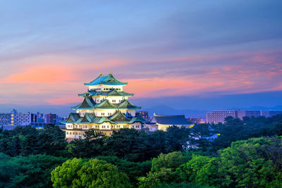 Illuminated buildings in city against sky during sunset