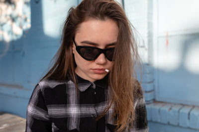 Beautiful woman wearing sunglasses with cigarette butt on lips 