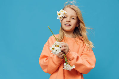 Young woman holding gift against blue background