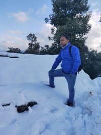 Boy standing on snow covered landscape against sky