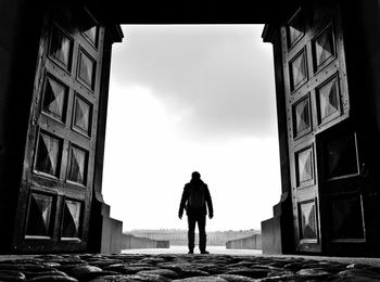 Rear view of man standing at entrance of old building