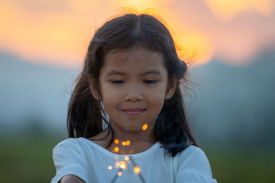 Smiling cute girl holding sparklers during sunset