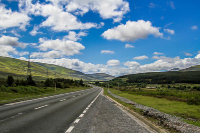 Empty road along landscape against sky