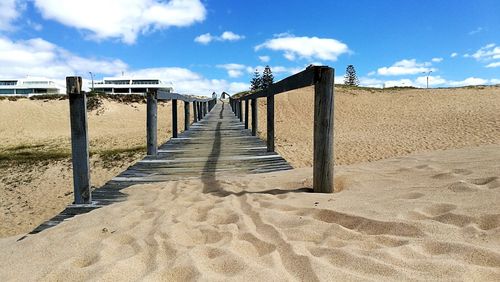 Wooden walkway on beach against sky