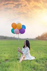 Full length of woman with balloons at field