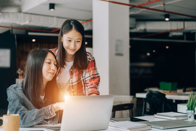 Portrait of young woman using phone on table