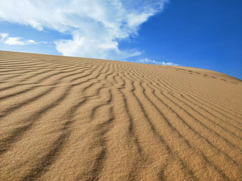 Sand dune in desert against blue sky