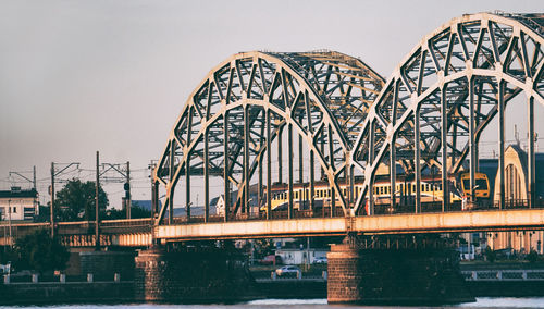 Bridge over river against sky in city